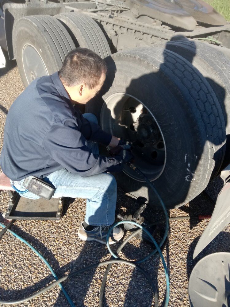 Technician working between dual tires on a roadside wheel service
